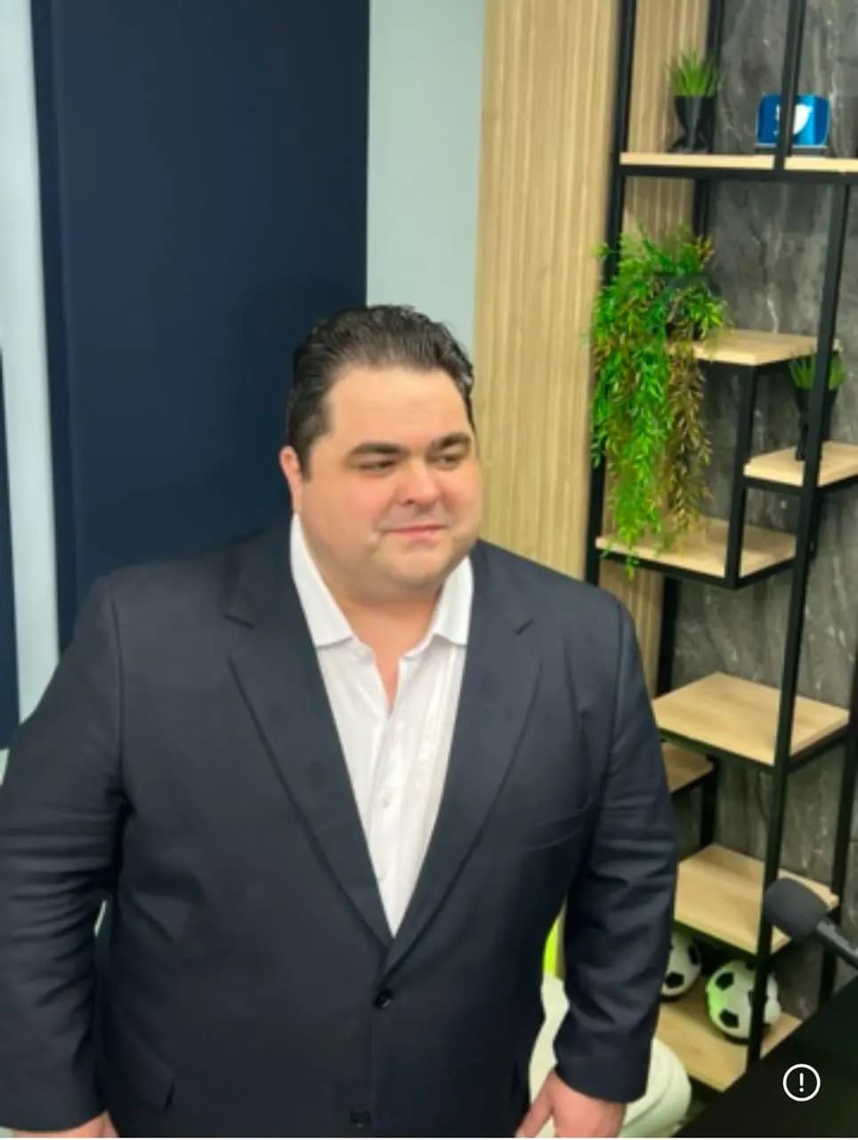 Mateus Gomes de paletó escuro em um ambiente de gravação